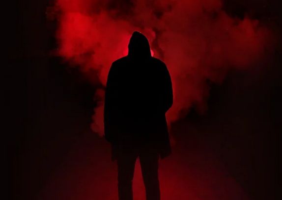 Férfi háttal áll sötét ruhában a piros színű füstben